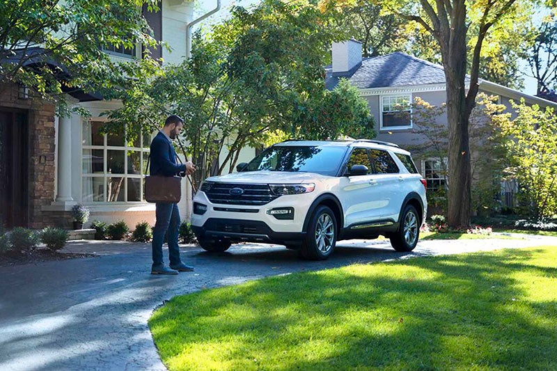 Exterior shot of man in front of house with a white Explorer® SUV cell phone in hand