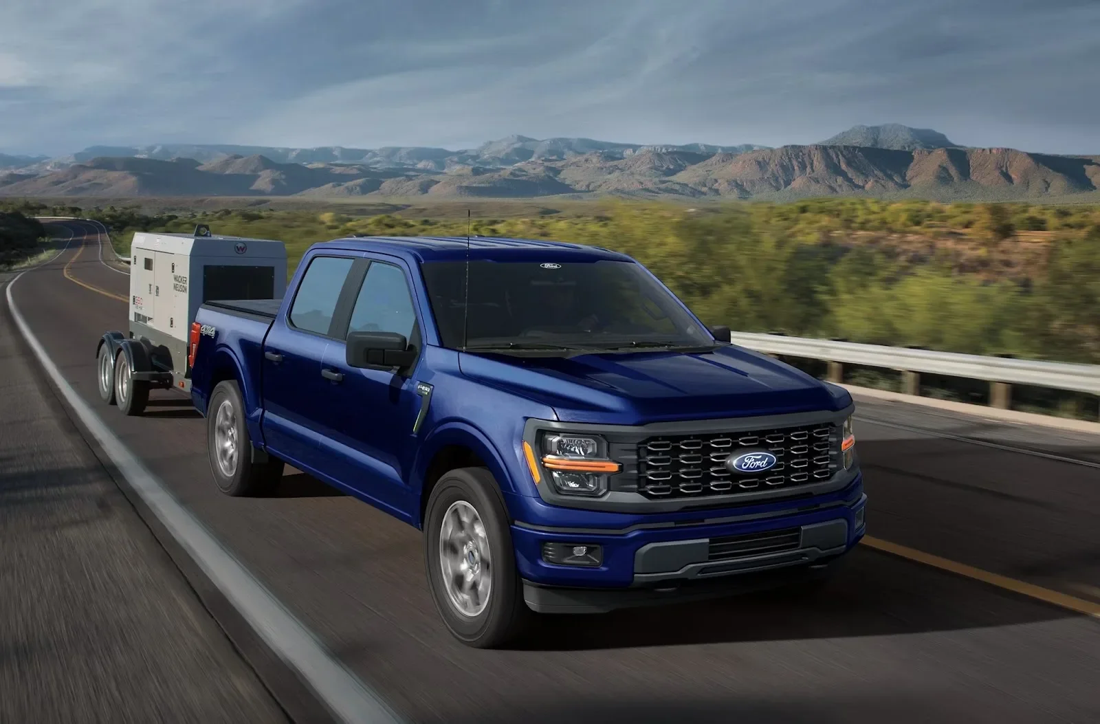 2026 Ford F-150 in Antimatter Blue Metallic towing a trailer on the road, front facing right