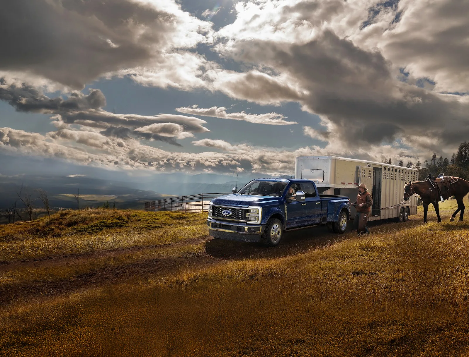 2026 Ford F-450 Super Duty King Ranch in Argon Blue towing a horse trailer, seen from the left front