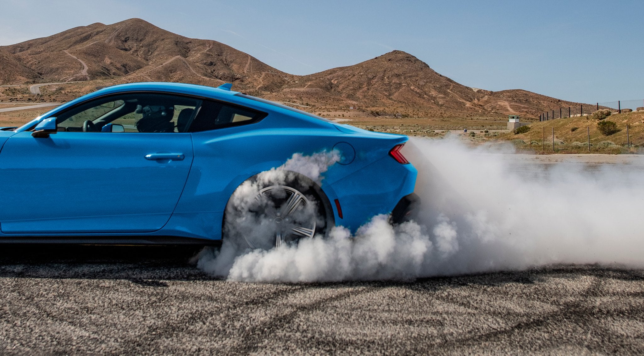 2026 Ford Mustang EcoBoost in Grabber Blue performing a burnout